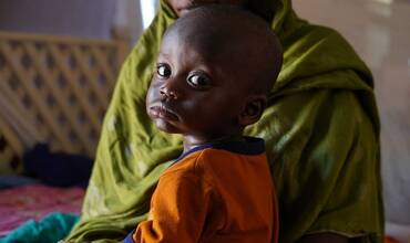 Un niño sudanés sentado con su madre