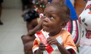 Una niña toma un sobre de alimento terapéutico proporcionado por UNICEF en Haití