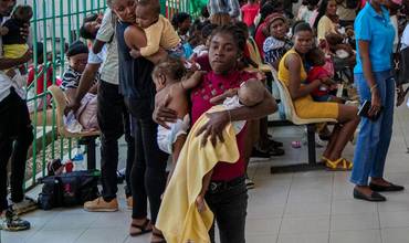 Una mujer lleva en sus brazos a dos bebés en uno de los colapsados hospitales de Haití