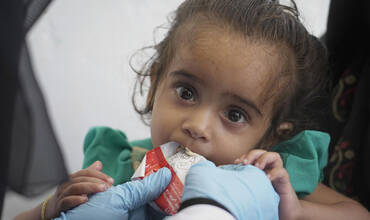 Una niña tomando alimentación terapéutica en una clínica de Yemen
