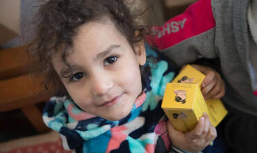 Una niña sostiene cajas de suplementos nutricionales suministrados por una clínica apoyada por UNICEF en Siria.