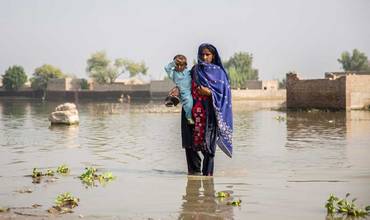 Una mujer lleva en brazos a su hijo en medio de las inundaciones que asolan Pakistán