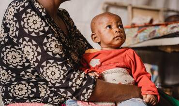 Merci, de 6 meses, acunada por su madre, Furaha, en la unidad de aislamiento y tratamiento de la viruela en el hospital Kavumu, apoyado por UNICEF, en la zona de salud de Miti-Murhesa, provincia de Kivu del Sur, RD del Congo, el 4 de septiembre de 2024.