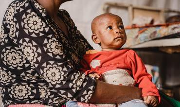 Merci, de 6 meses, acunada por su madre, Furaha, en la unidad de aislamiento y tratamiento de la viruela en el hospital Kavumu, apoyado por UNICEF, en la zona de salud de Miti-Murhesa, provincia de Kivu del Sur, RD del Congo, el 4 de septiembre de 2024.