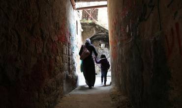 Una mujer palestina y su hija caminan por un callejón