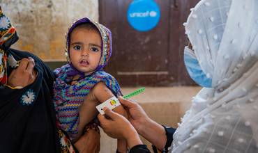 Personal sanitario mide la circunferencia del brazo de un bebé en Pakistán