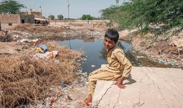 Mukaddar, de 10 años, sentado cerca de una zona inundada de su aldea de Geokaloi, en la provincia meridional paquistaní de Sindh.