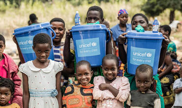 Niños y niñas sostienen cubos de agua limpia suministrados por UNICEF en Malawi