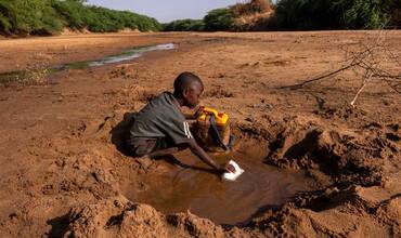 En Somalia, un niño recoge el poco agua que puede de un río seco debido a la grave sequía