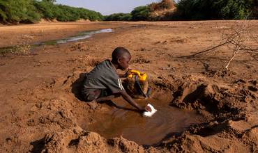 En Somalia, un niño recoge el poco agua que puede de un río seco debido a la grave sequía