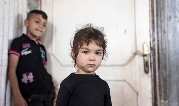 Hind, de 4 años, refugiada de Siria, junto a su familia en el exterior de la casa precaria en la que viven en Saida (Líbano).