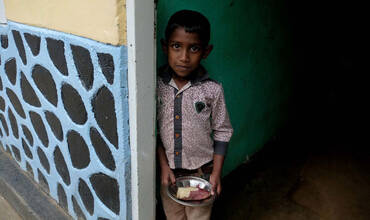 Un niño de Sri Lanka sostiene un plato de comida