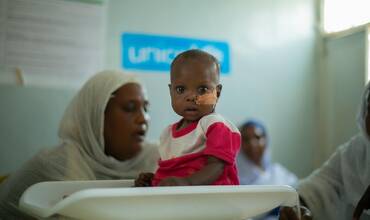 Un bebé sudanés sentado sobre una báscula en una de las clínicas que UNICEF apoya en el país