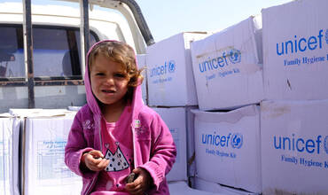 Una niña siria junto a los suministros de UNICEF distribuidos en su campamento de desplazados