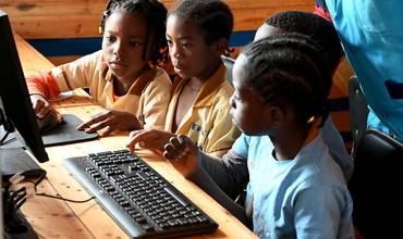 Niños aprendiendo con tablets y computadoras en una escuela pública de Camerún