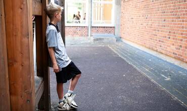 Imagen de recurso de un niño apoyado en una pared en la calle