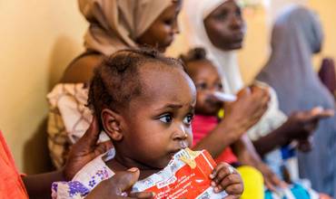 Una niña toma alimento terapéutico contra la desnutrición.