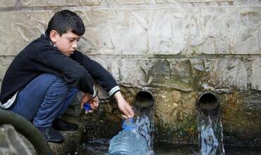 Un niño recoge agua potable en una aldea de Líbano
