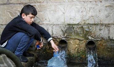 Un niño recoge agua potable en una aldea de Líbano