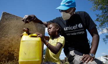 Un responsable de UNICEF y una niña recogen agua potable en Cabo Delgado, Mozambique