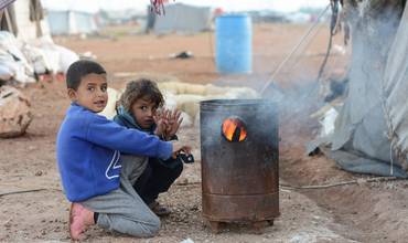 Niños refugiados de Siria al calor de una hoguera en el frío invierno