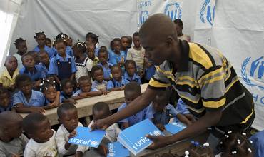 Una profesora reparte cuadernos