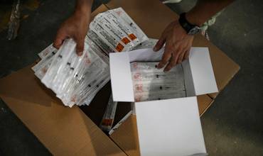 Personal de UNICEF revisa una caja de jeringuillas en un almacén de India