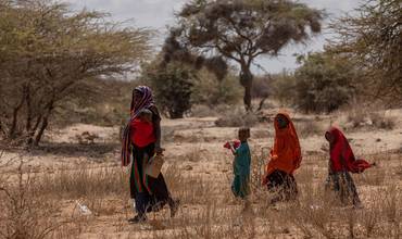 Una mujer y sus hijos caminan por el terreno seco 
