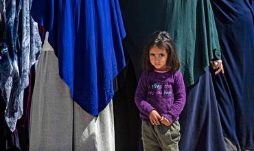 Una niña junto a un grupo de mujeres en un campamento para desplazados de Siria
