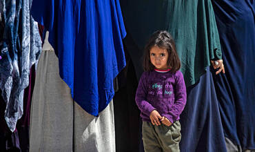 Una niña junto a un grupo de mujeres en un campamento para desplazados de Siria