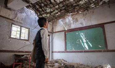 Un niño contempla las ruinas de su escuela en Hajjah
