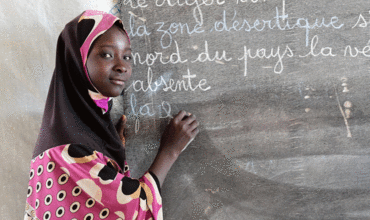 Una niña escribe en la pizarra de su aula