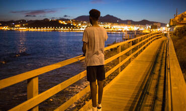 Un adolescente mira el mar desde la costa