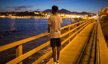 Un adolescente mira el mar desde la costa