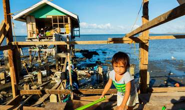 Un niño junto a su casa, que ha empezado a ser reconstruida por su familia