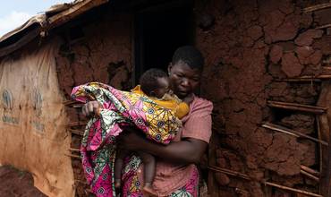 Una mujer sostiene en sus brazos a un bebé en el campamento de Rhoe, en la República Democrática del Congo
