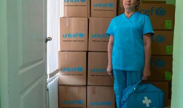 Mujer junto a cajas de suministros UNICEF