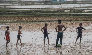 Jóvenes jugando con una pelota en zona de pobreza y catástrofe climático