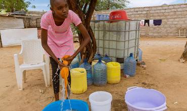 Joven aprovechando el sistema de agua impulsado con energía solar instalado por UNICEF