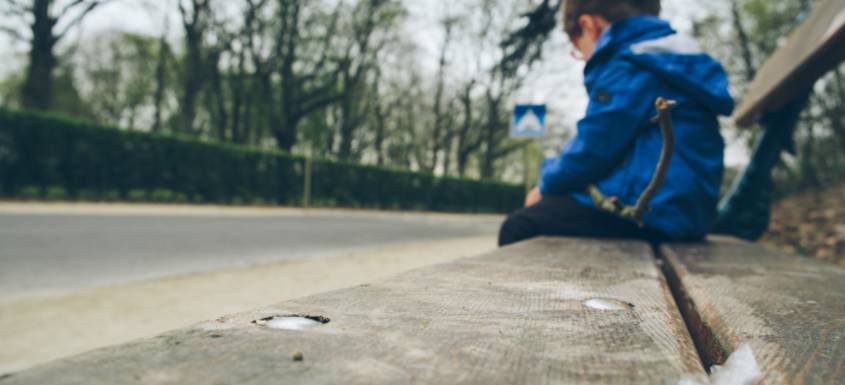 Un niño sentado en un banco.