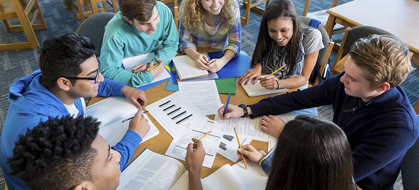 Un grupo de adolescentes estudia en grupo sobre una mesa redonda