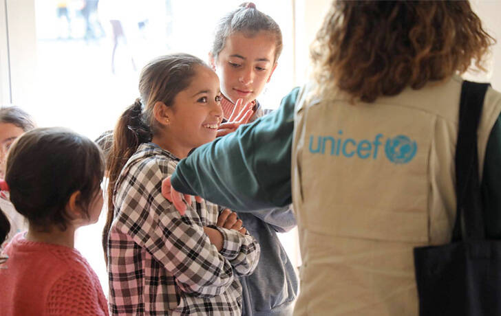 Una niña hablando con miembros del staff de UNICEF