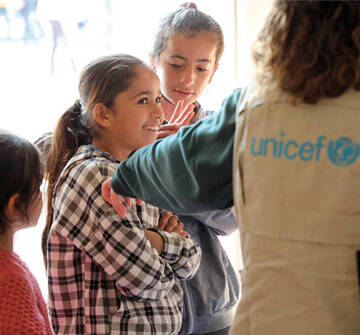 Una niña hablando con miembros del staff de UNICEF