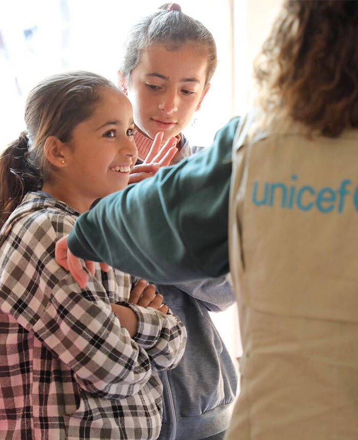 Una niña hablando con miembros del staff de UNICEF
