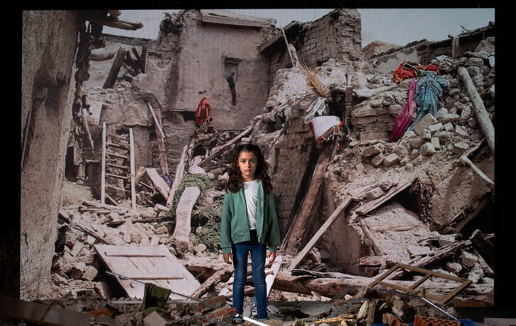 Niña frente a una pantalla donde se proyecta una imagen de una emergencia.