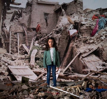 Niña frente a una pantalla donde se proyecta una imagen de una emergencia.