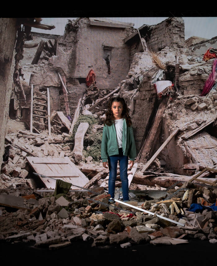 Niña frente a una pantalla donde se proyecta una imagen de una emergencia.