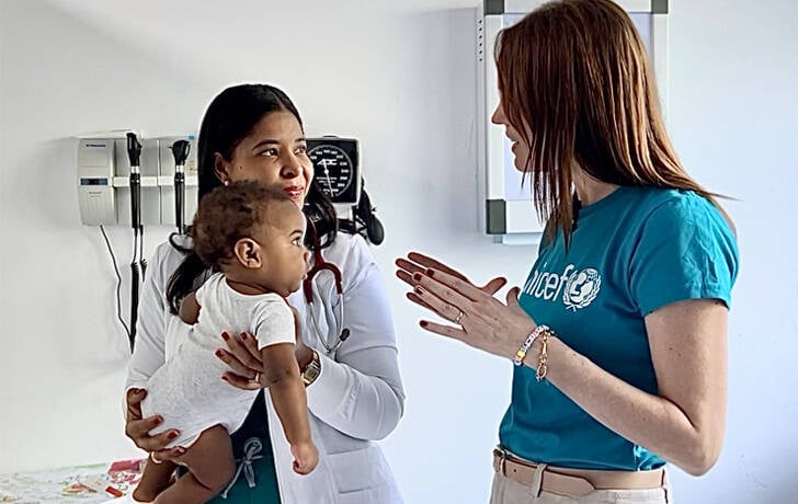 Un bebé mira con atención a staff de UNICEF.