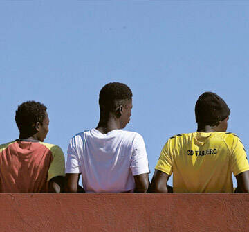 Niños migrantes no acompañados Un grupo de niños adolescentes de espaldas mirando hacia el horizonte