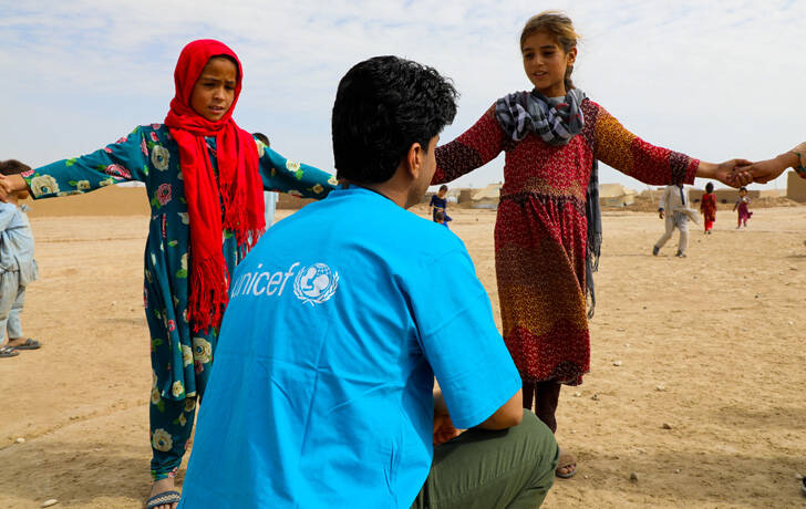 Nos quedamos para proteger a la infancia Niñas hablando con un miembro del staff de UNICEF